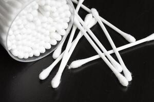 Macro view of white cotton ear cleaning buds arranged in black background nicely in a container photo