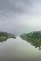 A landscape view of a calm river with green trees and mountain in India photo