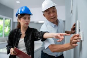 Senior home inspector checking the electrical switch and check defects, before finish handing it over to client. Young engineers learn home inspection with Senior, Real estate and renovation concept. photo