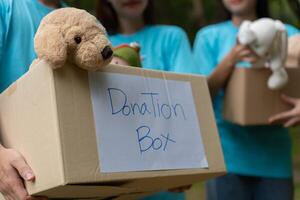 contento joven asiático estudiantes diverso voluntarios sostener donar caja y juguetes para caridad a compartir niños y orfanatos, un caridad para sostenibilidad. voluntario trabajo estilo de vida y social cooperación foto