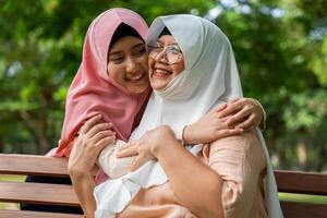 Muslim careful caregiver or nurse taking care of the patient in the hospital park. Happy Muslim mother in hijab hugging daughter. Concept of Savings and Senior Health Insurance, a Happy Family photo