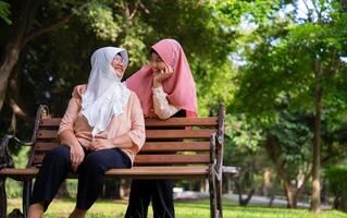 Muslim careful caregiver or nurse taking care of the patient in the hospital park. Happy Muslim mother in hijab hugging daughter. Concept of Savings and Senior Health Insurance, a Happy Family photo