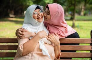 Muslim careful caregiver or nurse taking care of the patient in the hospital park. Happy Muslim mother in hijab hugging daughter. Concept of Savings and Senior Health Insurance, a Happy Family photo