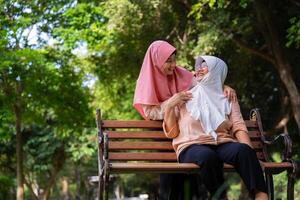 Muslim careful caregiver or nurse taking care of the patient in the hospital park. Happy Muslim mother in hijab hugging daughter. Concept of Savings and Senior Health Insurance, a Happy Family photo