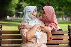 Muslim careful caregiver or nurse taking care of the patient in the hospital park. Happy Muslim mother in hijab hugging daughter. Concept of Savings and Senior Health Insurance, a Happy Family photo