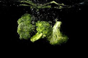 Broccoli pieces splash into the water photo