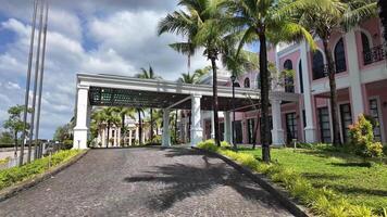 Luxurious tropical resort entrance with paved driveway, elegant portico, palm trees, and a pastel colored building, embodying an upscale vacation destination, Pho Quoc,Vietnam, 24 Jan, 2024 video