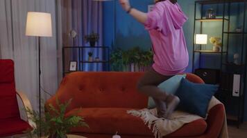 gelukkig volwassen vrouw in hoofdtelefoons dansen en jumping terwijl luisteren muziek- Bij huis alleen Aan sofa video