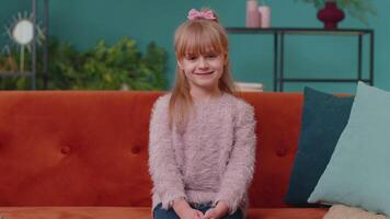 porträtt av liten förtjusande barn flicka Sammanträde ensam på soffa på Hem ser på kamera och leende video