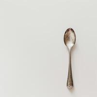 AI generated minimalistic style silver spoon on white background top view photo