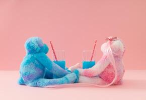 Romantic date. Creative composition made with pink and blue monkey dolls drinking exotic cocktails against pastel pink background. Minimal love concept. Trendy and funny romantic date idea. photo