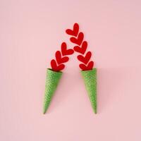 Summer love cream. Creative layout made with red hearts and green waffle ice cream cones on pink background. Minimal summertime love concept. Romantic ice cream idea. Flat lay. photo