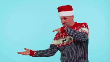 Man in red sweater Santa Christmas showing thumbs up and pointing empty place, advertising area video