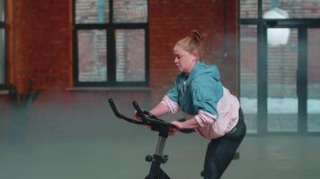 Woman performs aerobic endurance training workout cardio routine on the simulators, cycle training video