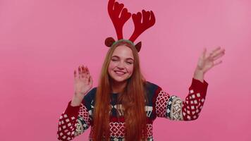 Young adult girl in Christmas deer antlers listening music, dancing disco fooling around having fun video