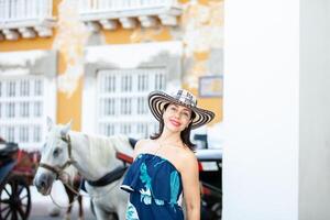 hermosa mujer vistiendo el tradicional Colombiana sombrero llamado sombrero vueltiao a el aduana cuadrado en el histórico calles de el cartagena Delaware indios amurallado ciudad foto