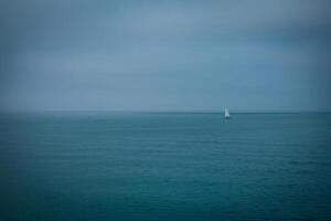 Seaside landscape with cloudy weather and a small boat on the horizon - minimal panorama view of the storm dark gloomy image photo