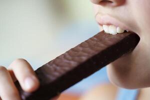 cosecha anónimo Adolescente niña comiendo delicioso chocolate proteína bar foto