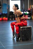 Relaxed mature sportswoman sitting on a box in the gym photo