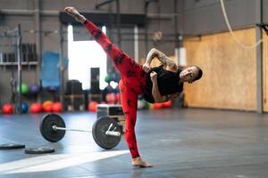 flexible juguetón mujer pateando en el gimnasio foto