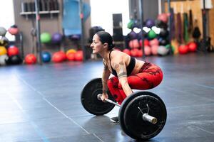 Mature sportive woman lifting weights in the gym photo