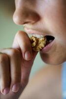 Anonymous girl eating healthy walnut kernel at home photo