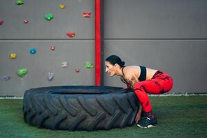 juguetón mujer levantamiento un camión rueda en un gimnasio foto