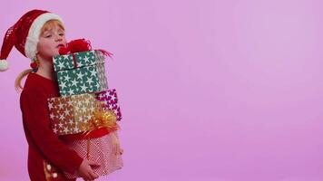 Girl in Christmas sweater, Santa hat, smiling, holding many gift boxes New Year presents shopping video