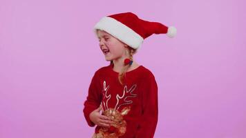 Girl in Christmas Santa sweater, hat dancing trendy dance for social media fooling around having fun video