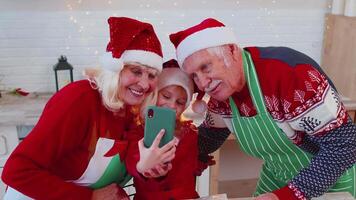 Senior grandparents with granddaughter kid taking selfie photo on mobile phone at Christmas kitchen video