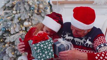 Grandchild girl kidexhcanging Christmas gift present boxes with happy elderly grandfather at home video