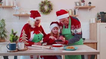 senior grootouders en kleinkind aan het kijken Koken les gebruik makend van digitaal tablet Bij Kerstmis keuken video