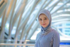 AI generated A smiling Malay woman in hijab at a modern building photo