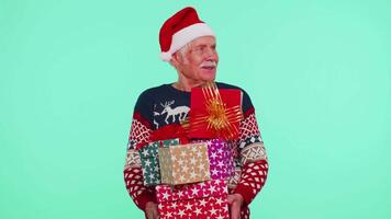 Senior grandfather man in Christmas sweater holding many gift boxes New Year presents shopping sale video
