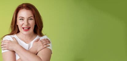 Cheerful charismatic happy good-looking redhead woman red lipstick cross hands chest smiling motivated excited having fun playful thrilled mood grinning enthusiastic standing green background photo