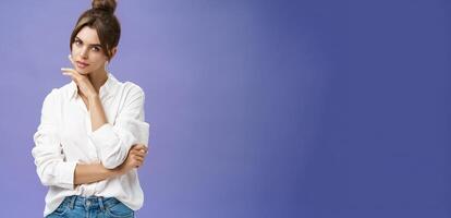 retrato de oferta y femenino elegante mujer en blanco blusa posando sensualmente y coqueta conmovedor barbilla mirando atrevido a cámara posando en contra púrpura antecedentes con seguro de sí mismo expresión foto