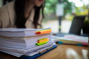 The pile of documents on the secretary's desk was prepared for the executives who would be attending the meeting. Several documents were stacked on the secretary's desk ready for the attendees. photo