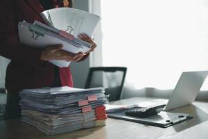 The pile of documents on the secretary's desk was prepared for the executives who would be attending the meeting. Several documents were stacked on the secretary's desk ready for the attendees. photo