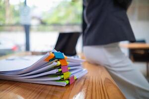 The pile of documents on the secretary's desk was prepared for the executives who would be attending the meeting. Several documents were stacked on the secretary's desk ready for the attendees. photo