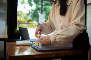 secretary is searching through pile of important documents on office table deliver them to manager for presentation in time at meeting. Concept of difficulty finding information from piles of document photo