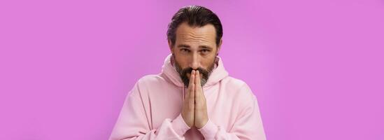 Worried intense serious-looking troubled handsome mature bearded man praying waiting important news nervously looking camera press palms supplicating wish wife alright, standing purple background photo