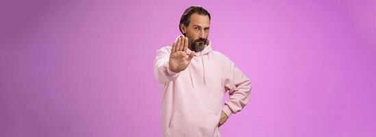 Stand right there. Portrait serious-looking bossy adult bearded father extend arm stop taboo no gesture forbidding come party look solid confident demanding quit, standing purple background photo