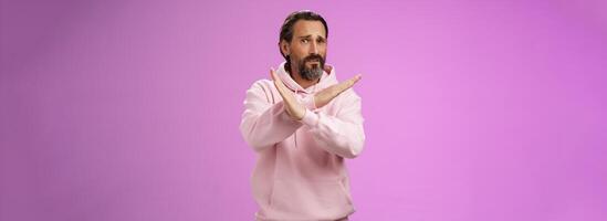 Portrait awkward displeased uncomfortable mature bearded husband begging make cross gesture refusing asking stop unwilling participate wife suspicious event standing intense express dislike photo