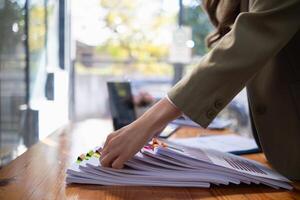 secretary is searching through pile of important documents on office table deliver them to manager for presentation in time at meeting. Concept of difficulty finding information from piles of document photo