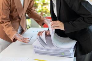 A young secretary receives a pile of documents to find important information for the company manager to use in a meeting. The concept of finding important documents from piles of overlapping documents photo