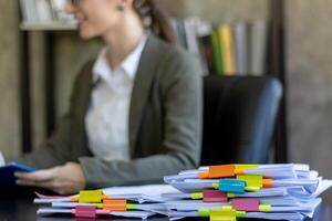 A young secretary receives a pile of documents to find important information for the company manager to use in a meeting. The concept of finding important documents from piles of overlapping documents photo