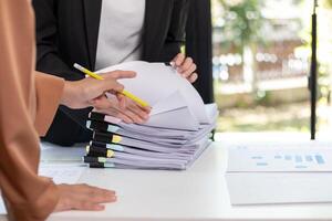 A young secretary receives a pile of documents to find important information for the company manager to use in a meeting. The concept of finding important documents from piles of overlapping documents photo