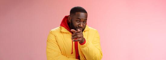 Guy suspecting you pointing camera index finger squinting disbelief unsure, standing pink background asking question look doubtful hesitant, express distrust wear yellow jacket red hoodie photo