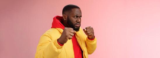 Serious-looking angry irritated young black bearded man pissed rude person attidude raise fists frowning grimacing anger furious feel punch face standing boxing pose wanna fight pink background photo