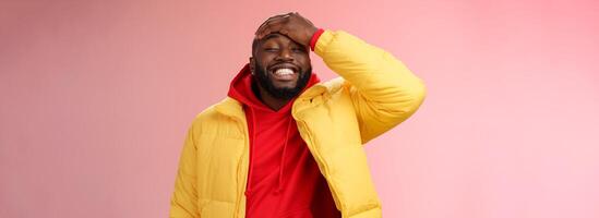 Charming cute black bearded 25s guy forget something stupid silly smiling friendly punch forehead grinning feel awkward say sorry standing pink background joyfully relaxed photo